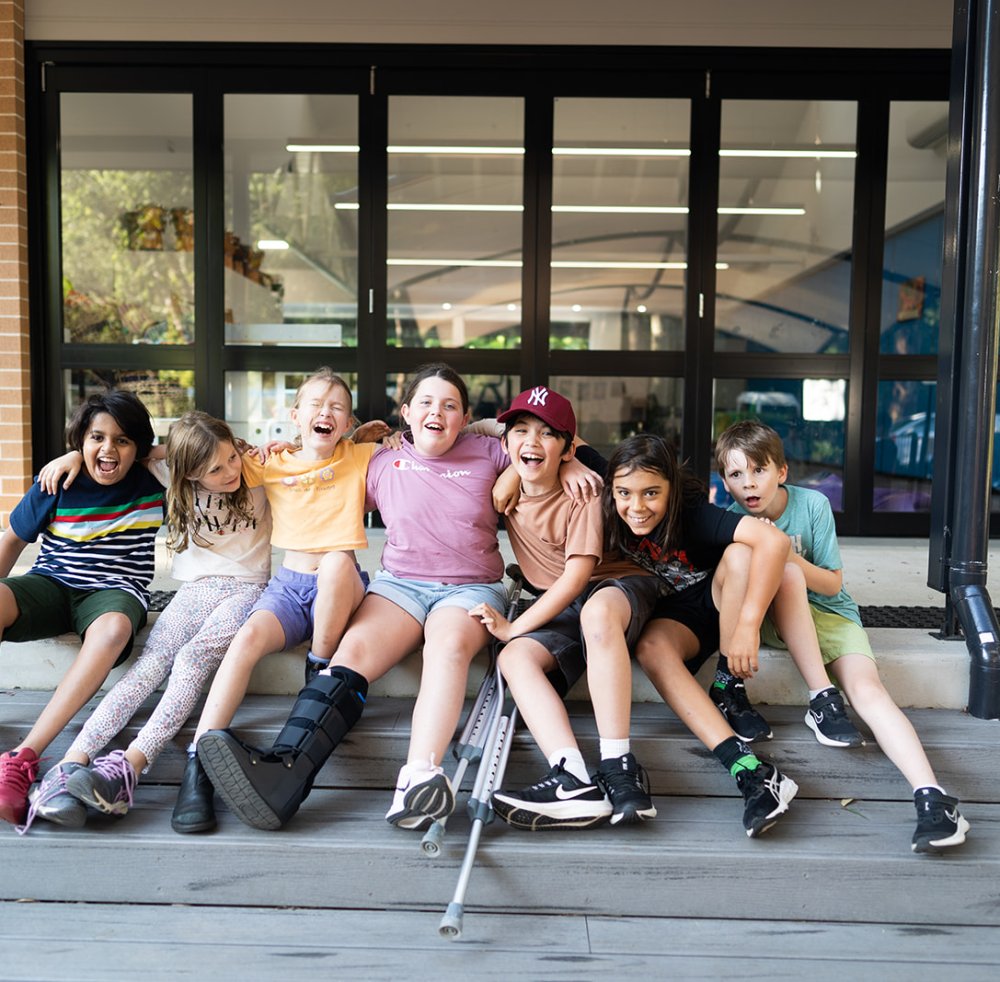 Children smiling and laughing out the front of a school